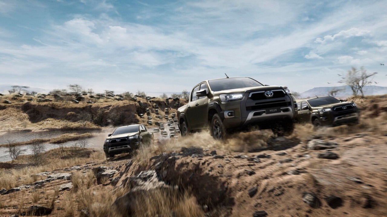 Multiple commerical Hilux models driving through scenic gravel terrain